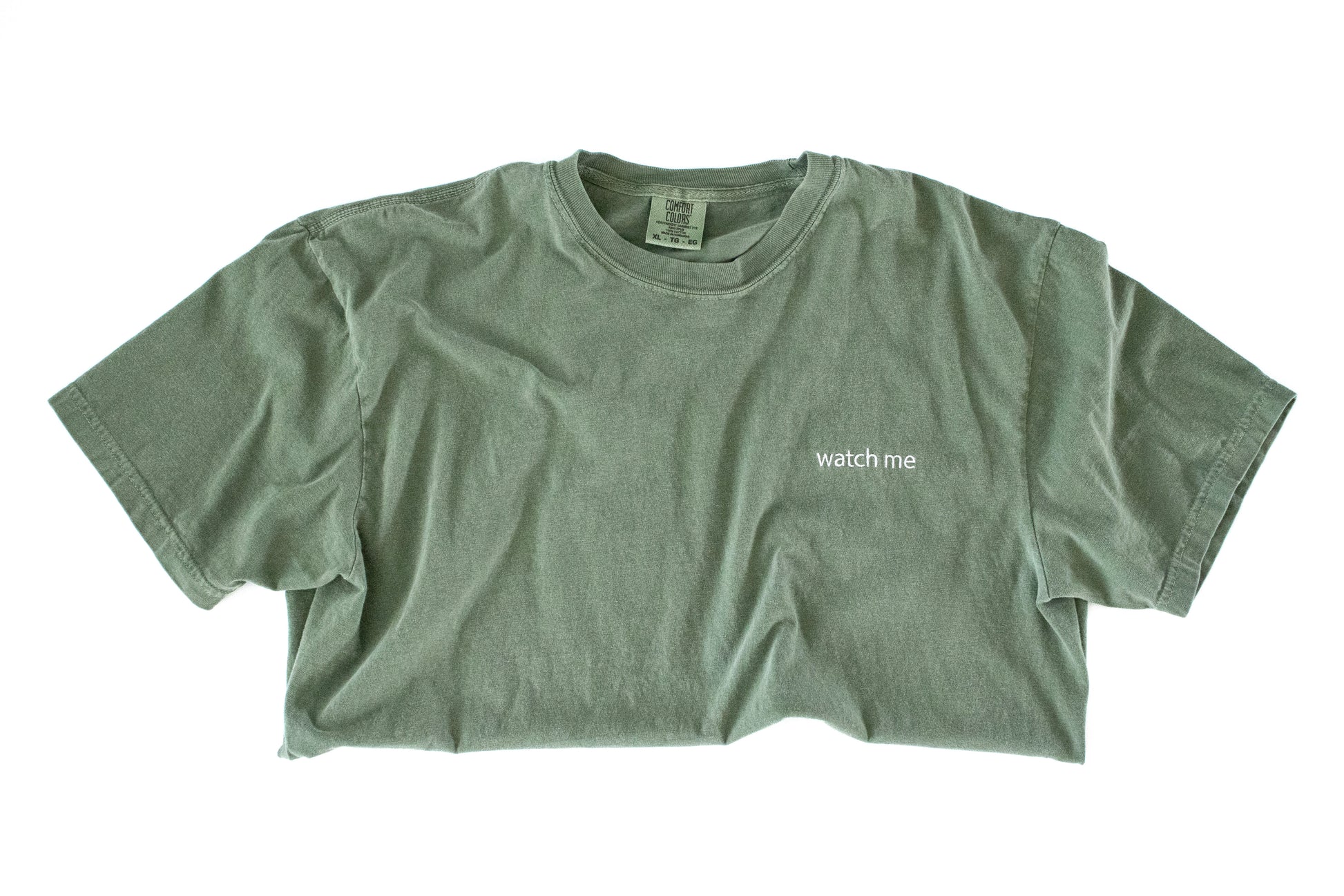 Green t-shirt with 'watch me' text on a white background
