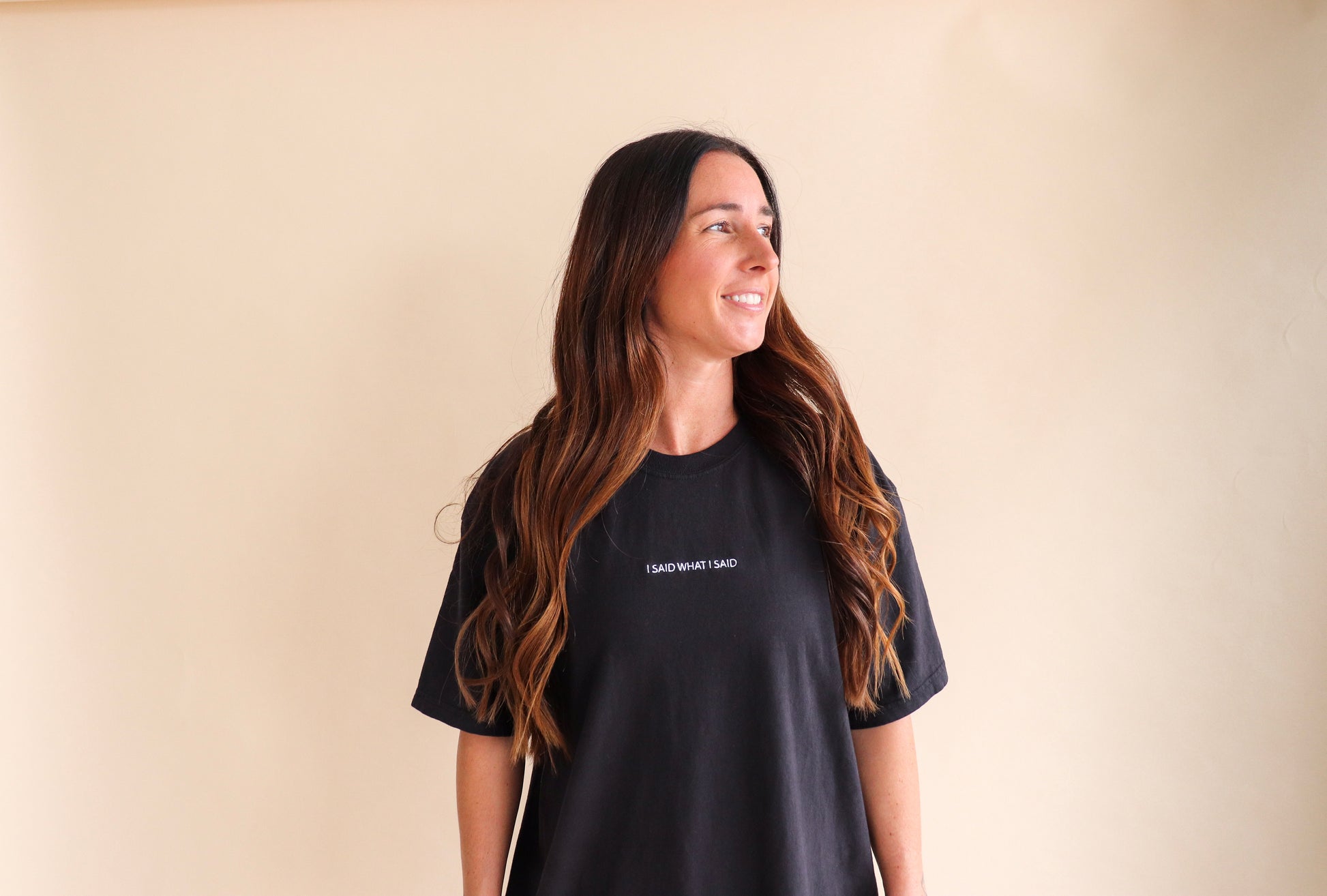 Woman wearing a black t-shirt with text saying I said what i said on a beige background